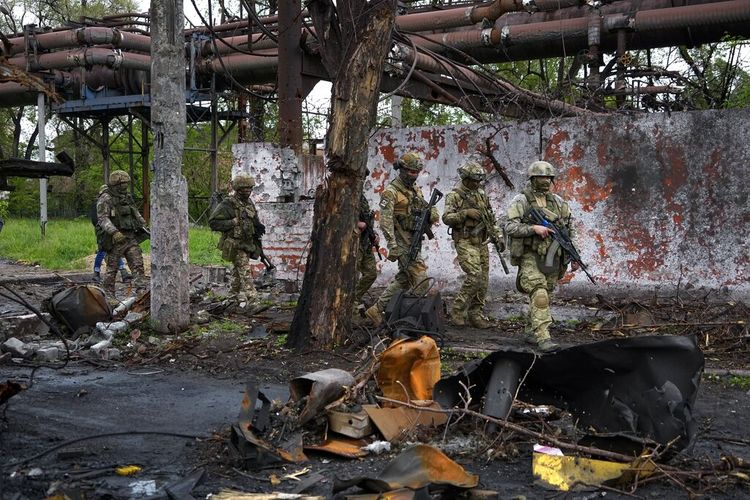 Pasukan Rusia berjalan di bagian yang hancur dari Pabrik Metalurgi Pekerjaan Besi & Baja Illich di Mariupol, di wilayah di bawah pemerintahan Republik Rakyat Donetsk, Ukraina timur, 18 Mei 2022.