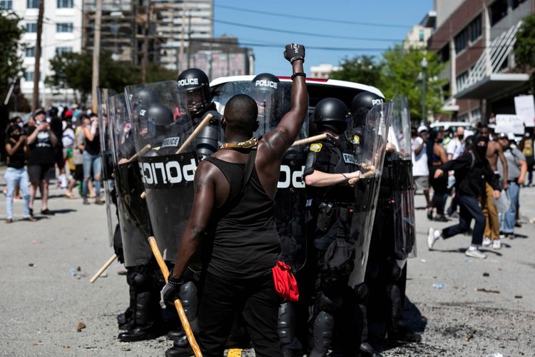 Seorang pengunjuk rasa mengacungkan kepalan tangannya di depan polisi saat reli protes atas kematian George Floyd saat ditahan oleh polisi Minneapolis, di Columbia, South Carolina, Amerika Serikat, Sabtu (30/5/2020).