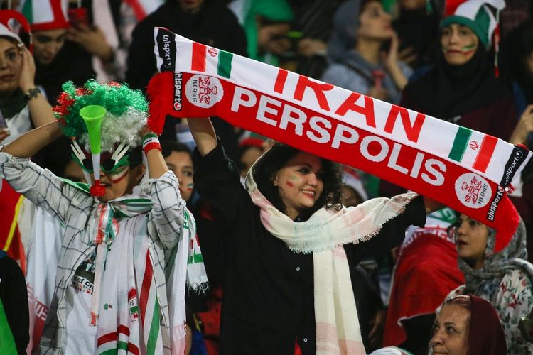 Iranian women cheer during the World Cup Qatar 2022 Group C qualification football match between Iran and Cambodia at the Azadi stadium in the capital Tehran on October 10, 2019. - The Islamic republic has barred female spectators from football and other stadiums for around 40 years, with clerics arguing they must be shielded from the masculine atmosphere and sight of semi-clad men. Women fans are attending the football match freely for the first time in decades, after FIFA threatened to suspend the country over its controversial male-only policy. (Photo by ATTA KENARE / AFP)