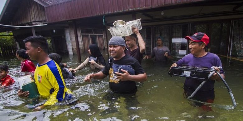 Warga menyelamatkan barang dari rumah yang terendam banjir di Desa Banua Raya di Kabupaten Tanah Laut, Kalimantan Selatan, Senin (11/01).