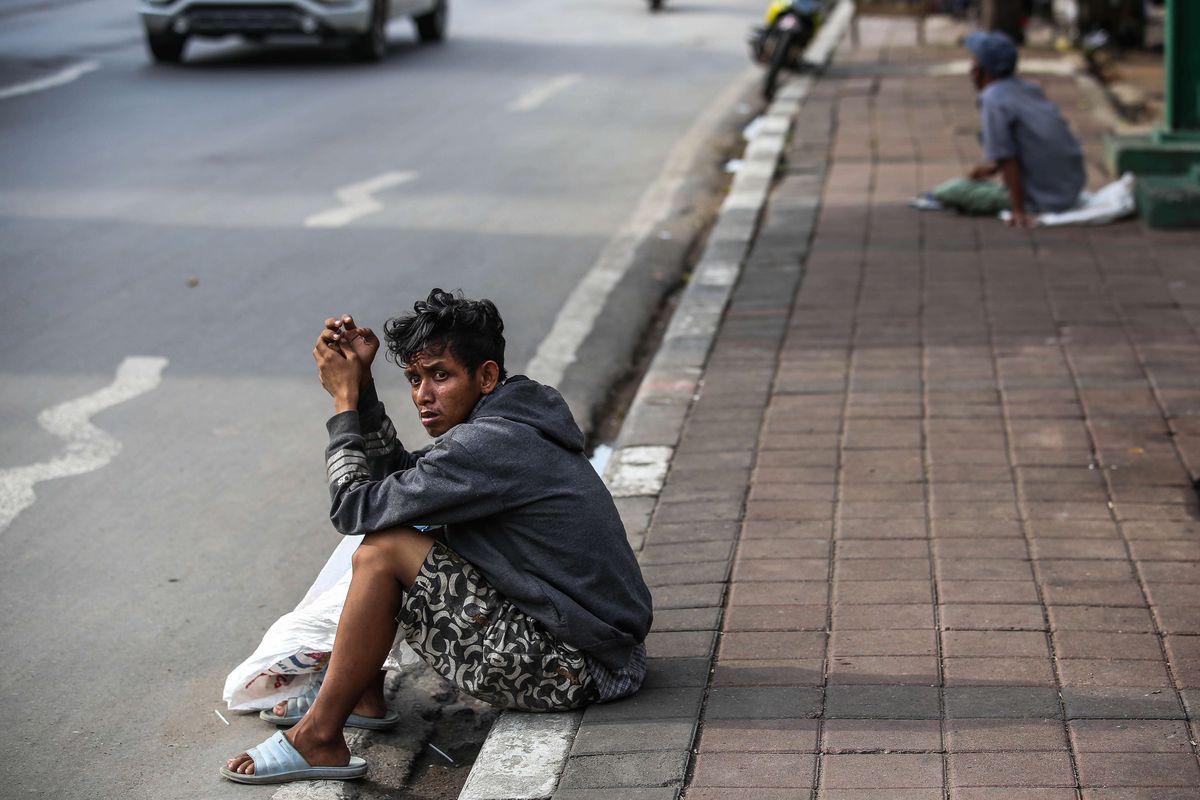 Tunawisma menggunakan masker saat duduk di trotoar di Jl. K.H. Mas Mansyur, Jakarta Pusat, Senin (4/5/2020). Provinsi DKI Jakarta memasuki pelaksanaan pembatasan sosial berskala besar (PSBB) yang diperpanjang ke tahap kedua. Tujuan PSBB ini adalah untuk menekan penyebaran virus corona (Covid-19).