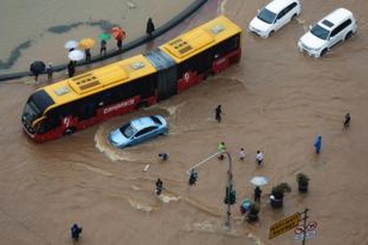 Sejumlah kendaraan mencoba melintasi genangan air di kawasan bundaran air mancur samping Patung Arjuna Wiwaha atau yang terkenal dengan sebutan Patung Kuda, Jakarta, Senin (9/2/2015).