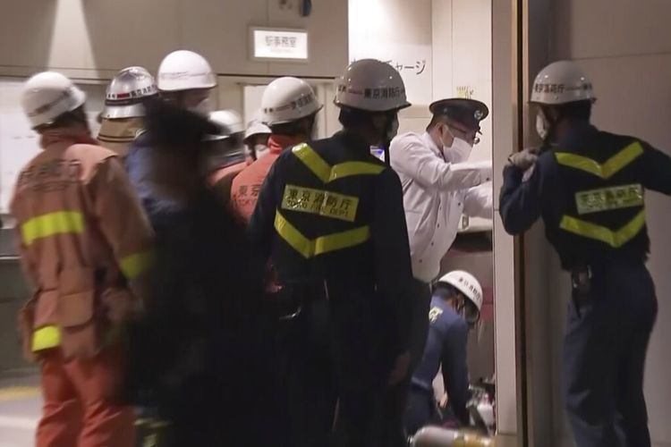 Petugas darurat dan polisi menyelidiki tempat kejadian di stasiun kereta api di Tokyo pada hari Minggu, 31 Oktober 2021, setelah seorang pria mengacungkan pisau di kereta komuter menikam beberapa penumpang sebelum menyalakan api, yang membuat orang-orang berebut untuk melarikan diri dan melompat dari jendela. , kata polisi dan saksi.