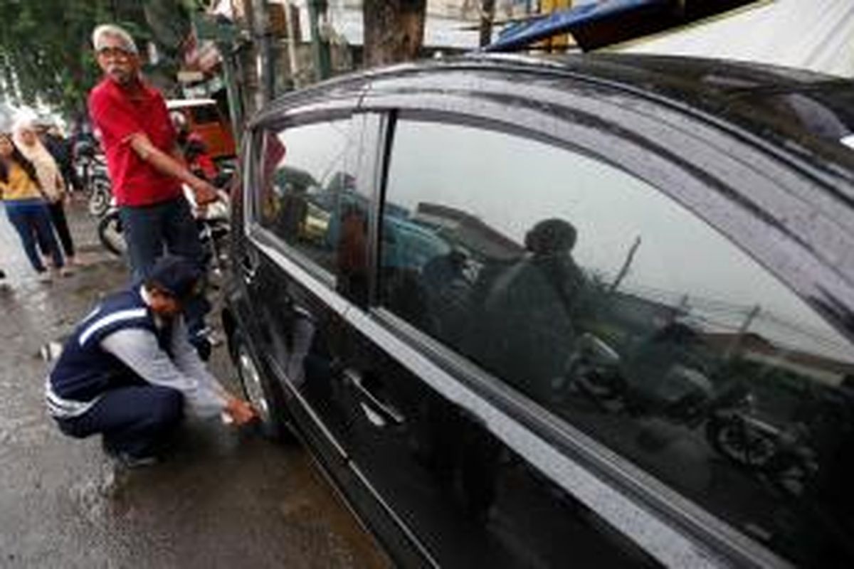 Petugas Dinas Perhubungan DKI Jakarta, Senin (10/3/2014), menggembosi ban mobil yang parkir di area larangan parkir di Jalan Otto Iskandar Dinata, Jakarta Timur. Sejumlah pemilik kendaraan bermotor masih membandel parkir liar, meski rambu larangan parkir sudah jelas terpasang. KOMPAS/LUCKY PRANSISKA 
