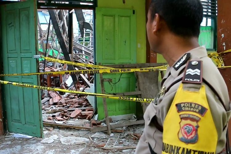 Seorang polisi menunjukan lokasi kelas yang ambruk di SMPN 2 Plumbon, Desa Gombang, Kecamatan Plumbon, Kabuaten Cirebon, Jawa Barat, Selasa (1/10/2019). Polisi telah memasang garis polisi di dua ruang kelas tersebut karena kondisinya masih sangat membahayakan.