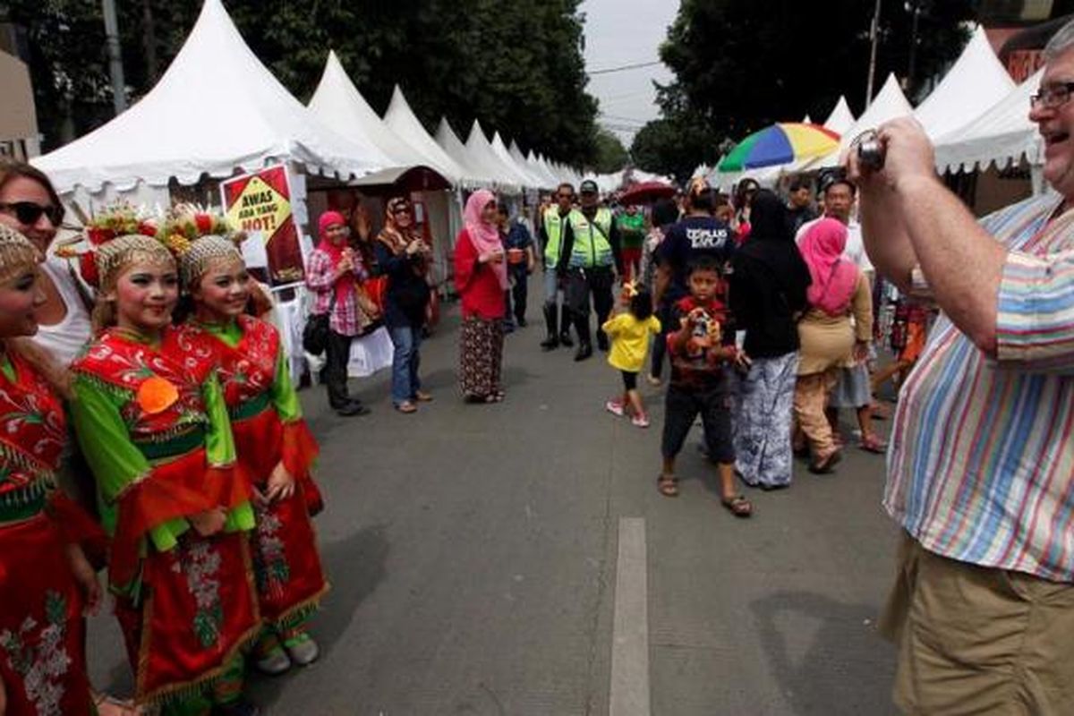 Pekerja ekspatriat berfoto dengan penari lenggang nyai di acara Festival Palang Pintu di Jalan Kemang, Jakarta, Sabtu (8/6/2013). Festival budaya dan kuliner Betawi tersebut telah diselenggarakan kedelapan kalinya dalam rangka HUT ke-486 DKI Jakarta dan akan berlangsung 8-9 Juni 2013. KOMPAS/LUCKY PRANSISKA