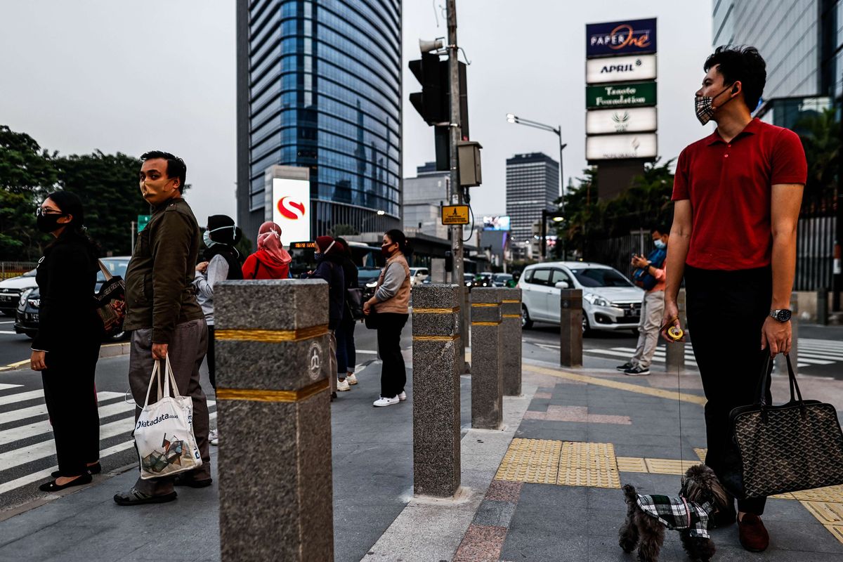 Masked office workers in Jakarta start to head home after a day at the office on 29/7/20