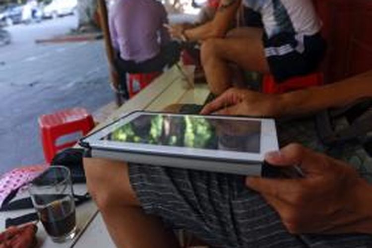 Seorang warga Vietnam menikmati layanan wi-fi gratis di sebuah kafe untuk menjelajahi dunia maya melalui perangkat tabletnya.