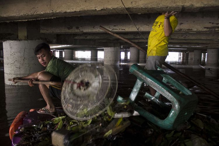 Petugas membersihkan sampah-sampah yang berada di sekitar Underpass Ghandi, Kemayoran, Jakarta Pusat, Minggu (2/2/2020). Jalan lintas bawah tersebut kembali tergenang banjir hingga ketinggian 2 meter.