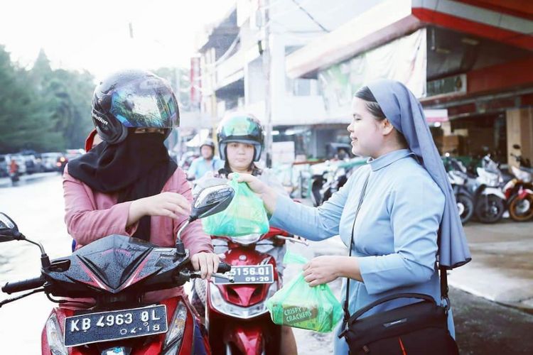 Suster Maria Seba SFIC (kanan) saat membagikan bingkisan berbuka puasa kepada pengendara di seputaran Gereja Katedral Santo Yosef, Pontianak, Kalimantan Barat (8/6/2018)