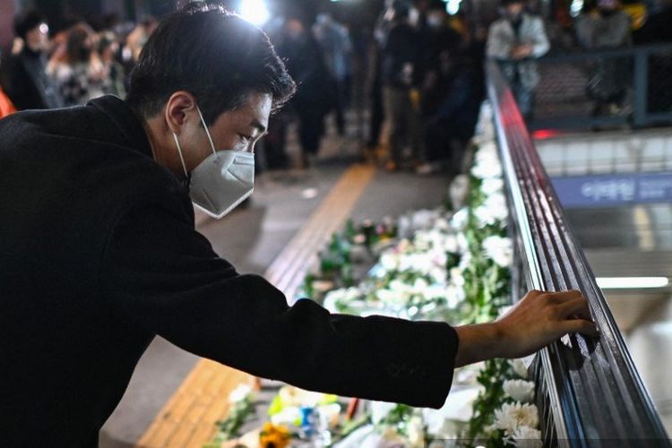 Usai tragedi Halloween Itaewon, seorang pria meninggalkan pesan di peringatan darurat di luar stasiun kereta bawah tanah Itaewon, Seoul, Korea Selatan, Minggu (30/10/2022).