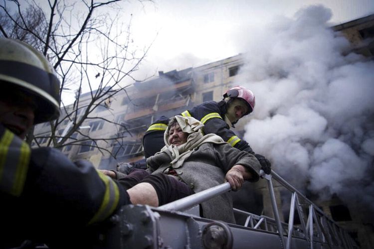 Dalam foto yang dirilis oleh layanan pers Layanan Darurat Negara Ukraina, petugas pemadam kebakaran mengevakuasi seorang wanita tua dari sebuah gedung apartemen yang terkena tembakan di Kyiv, Ukraina, Senin, 14 Maret 2022.