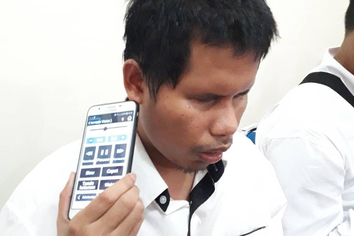 Penyandang disabilitas netra (PDSN) sedang mendengarkan audio dari smartphone.