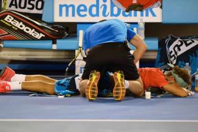 Petenis Spanyol, Rafael Nadal mendapat perawatan dari tim medis karena sakit pada pinggangnya, saat menghadapi petenis Swiss, Stanislas Wawrinka pada laga final Australian Open, Minggu (26/01/2014). Wawrinka menang 6-3, 6-2, 3-6, 6-3.
