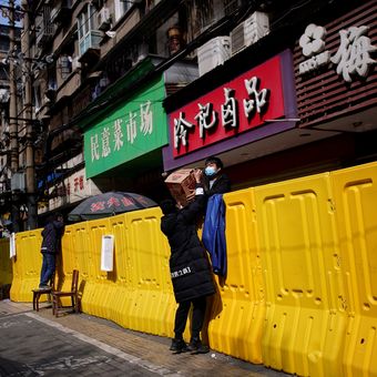 Pembeli membayar makanan melalui pagar pembatas di pasar basah Wuhan. Foto diambil pada 1 April 2020.