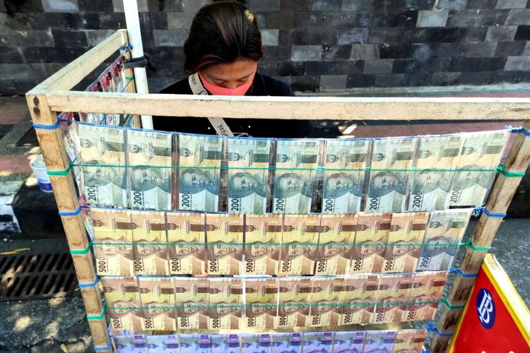 Seorang perempuan muda menjaga lapak penjualan jasa penukaran uang angpao lebaran di Jalan Kenanga, Kota Blitar, Selasa (27/4/2021)