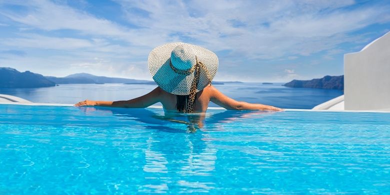 Seorang wanita sedang berenang di kolam renang di Santorini, Yunani.