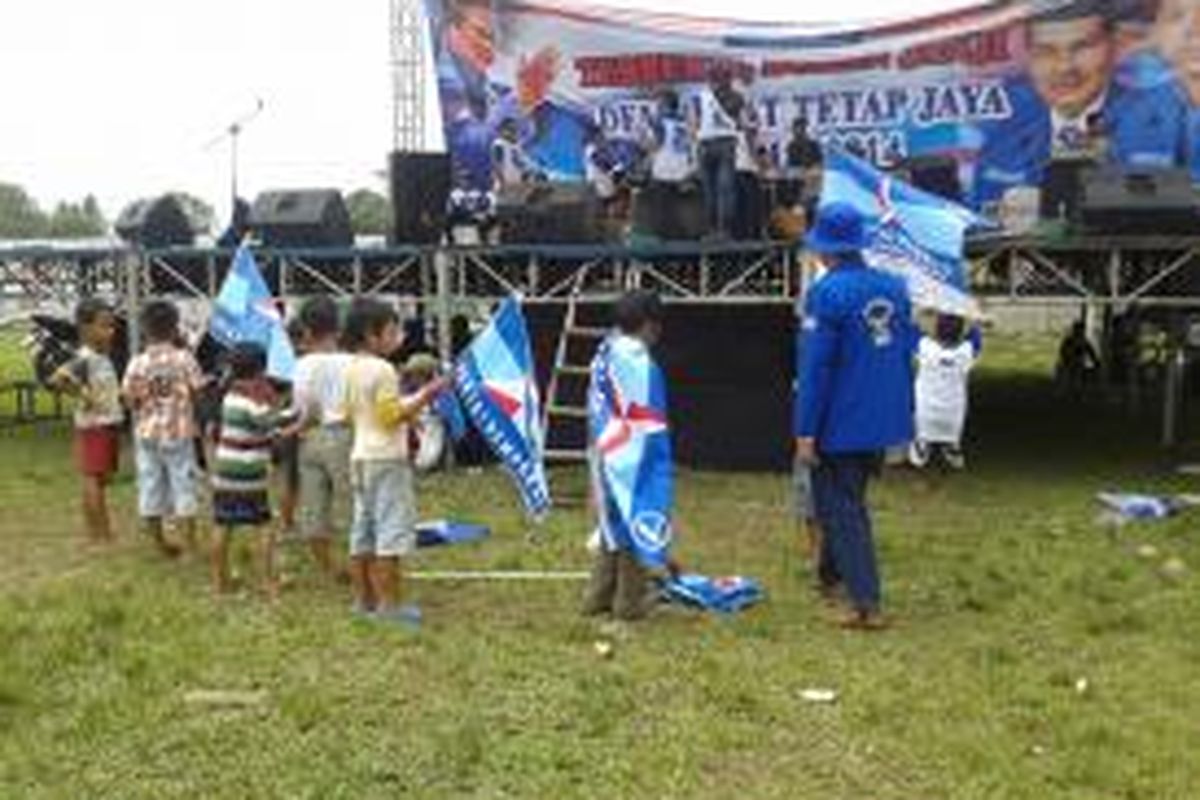 Sejumlah bocah kibarkan bendera Partai Demokrat di depan panggung musik saat kampanye di Lapangan Ciapus, Kecamatan Ponangan, Tangerang, Selasa (18/3/2014)