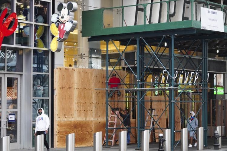 Para pekerja memasang papan pelindung pada sebuah toko di Times Square di New York, Amerika Serikat, pada 1 November 2020. Langkah tersebut dilakukan saat para peretail berupaya melindungi properti dari penjarahan atau kerusuhan lainnya dalam beberapa hari mendatang.