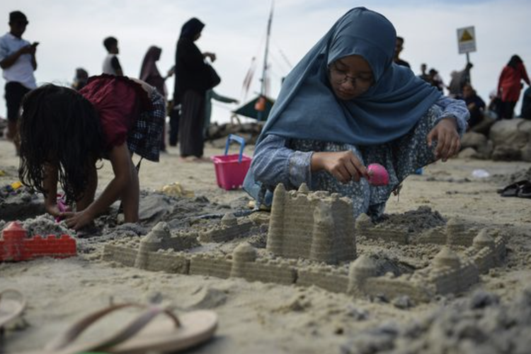 Anak-anak bermain pasir di Pantai Ancol, Sabtu (23/4/2023).