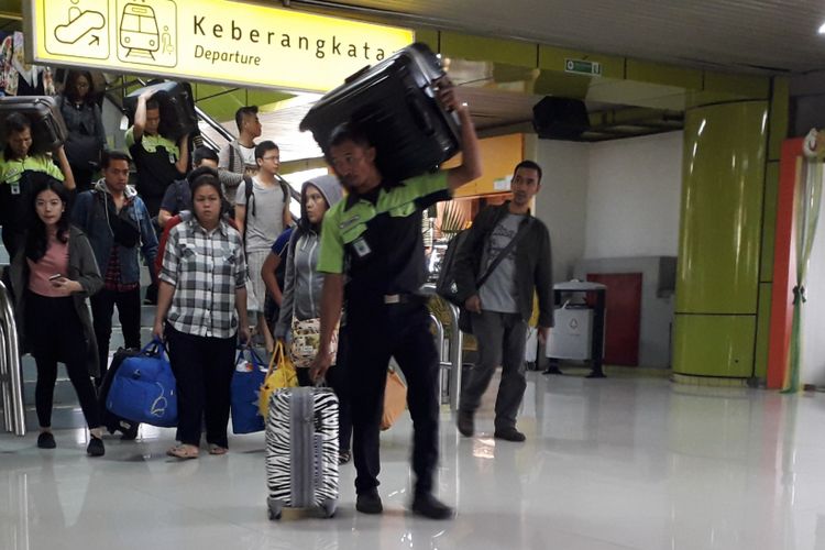 Seorang porter tengah membawa koper milik penumpang di Stasiun Gambir, Jakarta Pusat, Sabtu (9/6/2018).