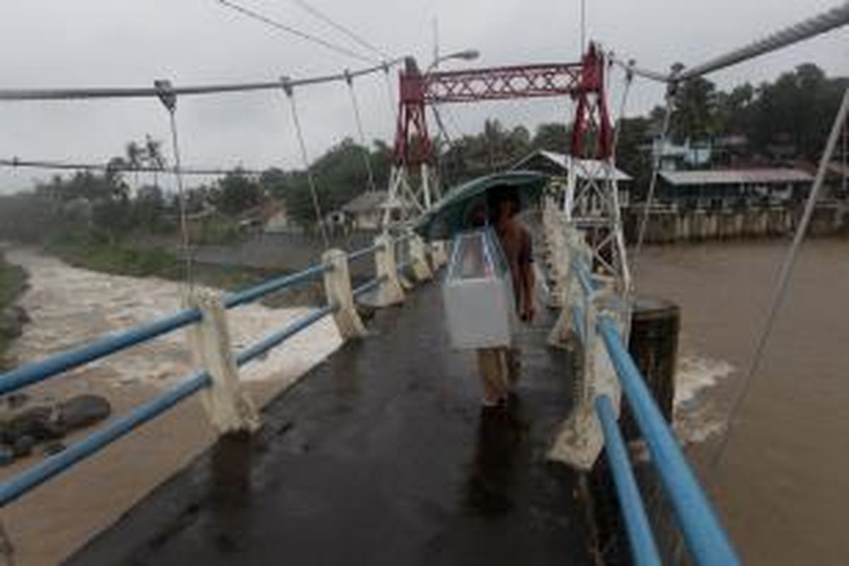 Warga melintas Bendungan Katulampa, Bogor, Jawa Barat, saat hujan lebat mengguyur Bogor, Rabu (9/1/2013). Ketinggian air di Bendungan Katulampa mencapai 120 sentimeter melebihi batas normal yaitu 50 sentimeter sehingga ditetapkan status siaga tiga. Warga terutama yang tinggal di daerah bantaran-bantaran sungai dihimbau bersiaga dan mengantisipasi datangnya banjir. KOMPAS IMAGES/KRISTIANTO PURNOMO