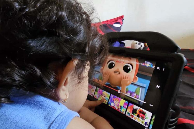 Seorang balita menggulir thumbnail di YouTube secara mandiri di tablet.