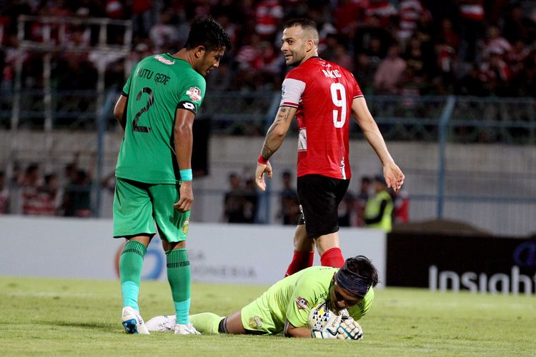 Penjaga gawang Bhanyangkara FC, Wahyu Tri mengamankan bola dari pemain Madura United Aleksandar Rakic  (kanan) pada Pekan 28 Liga 1 2019 yang berakhir dengan skor 1-2 di Stadion Gelora Bangkalan, Jawa Timur, Jumat (22/11/2019) malam.