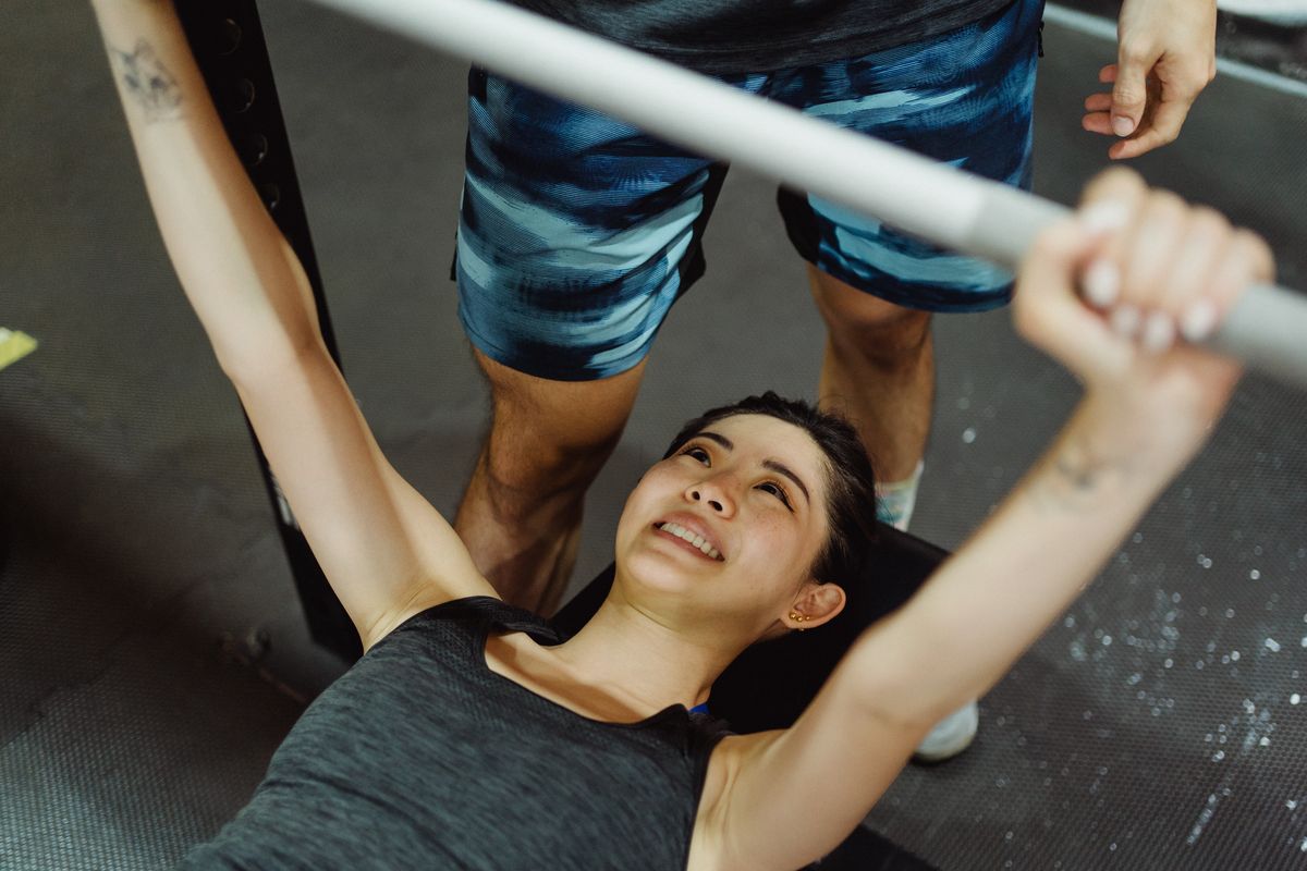 Ilustrasi perempuan yang sedang melakuikan bench press