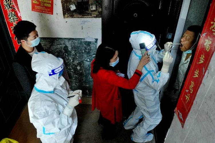 Pejabat dan petugas medis melakukan tes virus Covid-19 pada seorang warga yang diisolasi di rumah menyusul wabah virus corona baru-baru ini di Dexing, di provinsi Jiangxi tengah China, pada 3 November 2021.