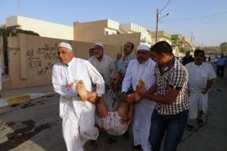 Warga kota Kirkuk, Irak menggotong seorang korban luka dalam sebuah serangan bom di sebuah masjid saat umat Sunni selesai menjalankan ibadah Shalat Id, Selasa (15/10/2013). Tragedi itu menewaskan 12 orang dan melukai puluhan orang lainnya.