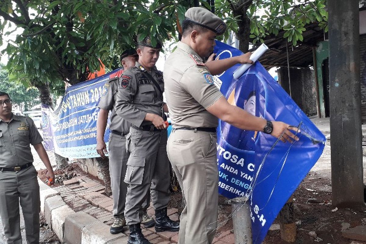 Satpol PP Jakarta Barat mencopot alat peraga kampanye yang memanfaatkan rambu lalu lintas dan petunjuk jalan di kawasan Srengseng, Kembangan, Jakarta Barat pada Selasa (23/10/2018)