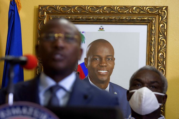 Foto mendiang Presiden Haiti Jovenel Moise tergantung di dinding bekas kediamannya, di belakang Perdana Menteri sementara Claude Joseph memberikan konferensi pers di Port-au-Prince, Selasa, 13 Juli 2021. 