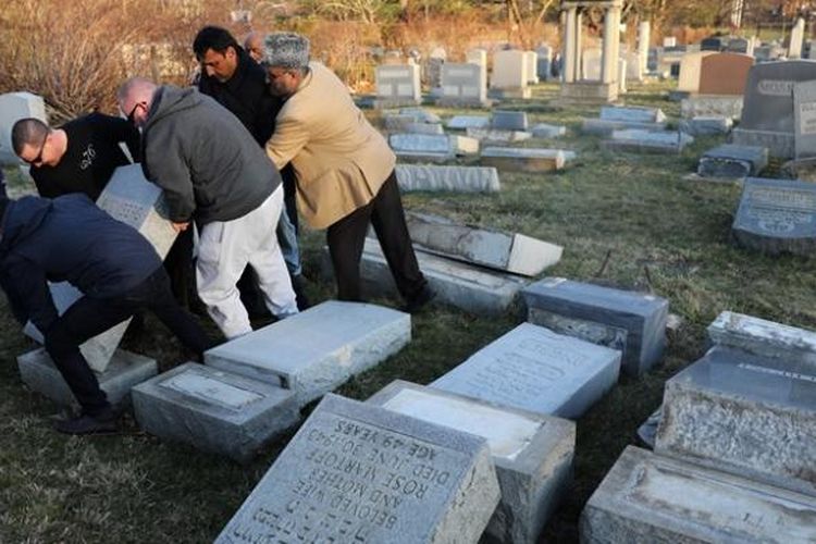 Sejumlah orang bekerja sama membereskan batu-batu nisan di pemakaman Yahudi Mount Carmel yang dirusak orang-orang tak bertanggung jawab.