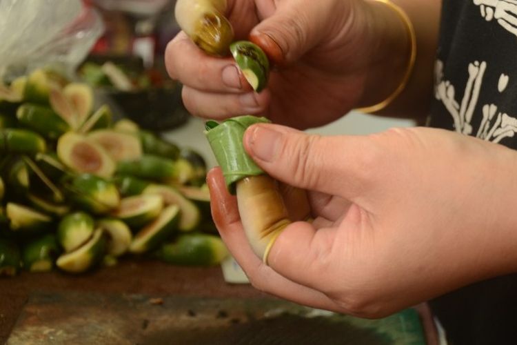 Penjual buah pinang, membungkus buah pinang dengan daun sirih. 