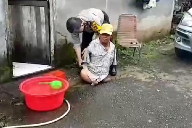 Kanit SPKT Polres Pangkep, Sulawesi Selatan, Aiptu Andi Syamsuddin memakaikan baju yang bersih kepada Oki, penyandang disabilitas tanpa tangan dan kaki.