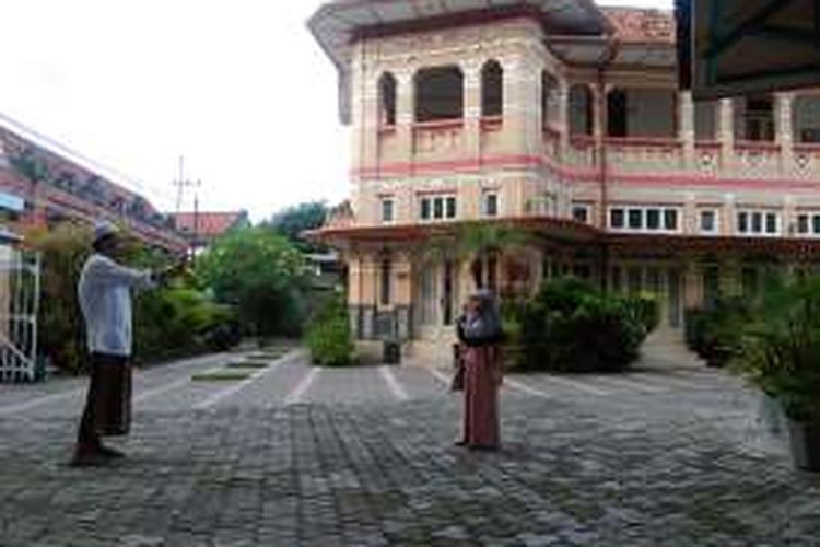 Warga berfoto dengan latar belakang rumah Gajah Mungkur di Gresik, Jawa Timur.