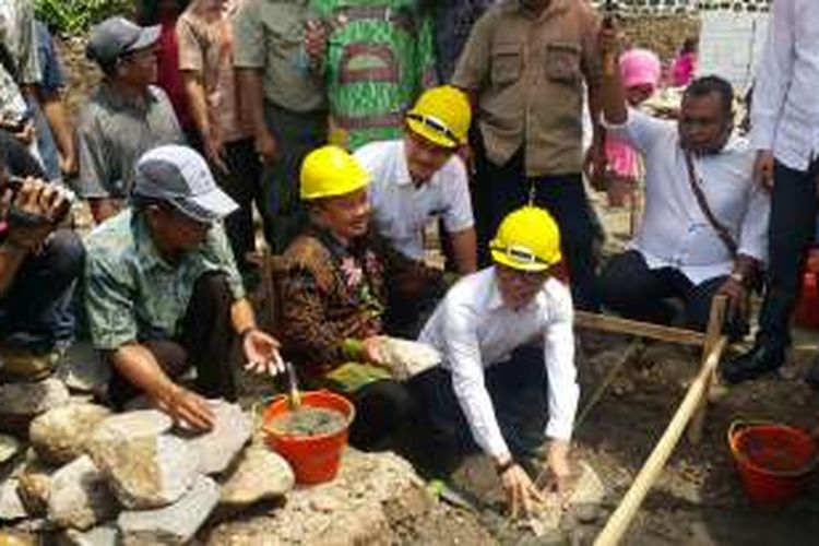 Menteri Tenaga Kerja dan Transmigrasi Hanif Dhakiri (helm kuning kanan) didampingi Bupati Madiun Muhtarom meletakkan batu pertama pembangunan rumah murah bagi TKI di Kelurahan Karangrejo, Kecamatan Wungu, Kabupaten Madiun, Selasa ( 20/12/2016) siang. 