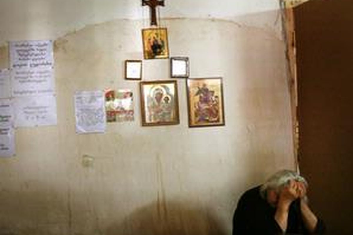 Seorang perempuan warga Gori Georgia menyangga kepalanya saat menunggu pembagian roti, Kamis (14/8).