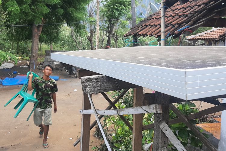 Iwan Purwanto berjalan menuju panel surya di rumahnya di Dusun Merak, Desa Sumberwaru, Kecaatan Banyuputih, Kabupaten Situbondo, Senin (24/10/2022).

