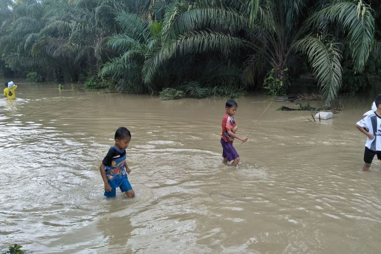 Anak-anak melintas di jalanan Desa Lawang, Kecamatan Matangkuli, Aceh Utara yang terendam banjir, Selasa (12/11/2019)