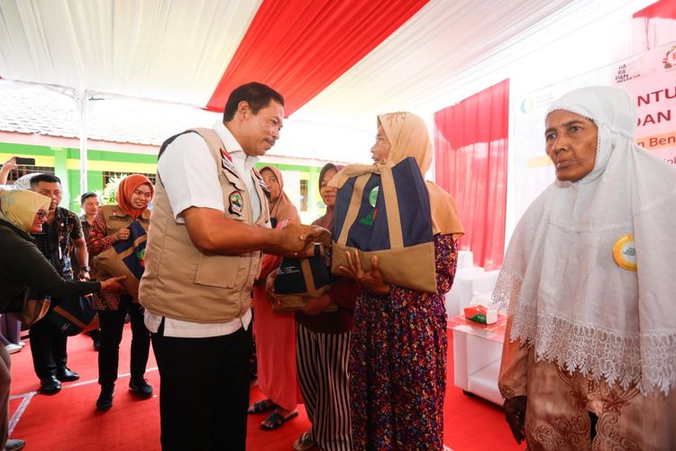 Penjabat (Pj) Gubernur Jateng Nana Sudjana memberikan bantuan pangan kepada salah satu warga yang terkena dampak dari bencana banjir di Kabupaten Demak, Provinsi Jawa Tengah, Minggu (24/3/2024).