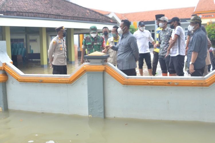 Bupati Gresik Fandi Akhmad Yani (tengah), saat melihat banjir luapan air Kali Lamong di Kecamatan Benjeng, Jumat (11/2/2022).