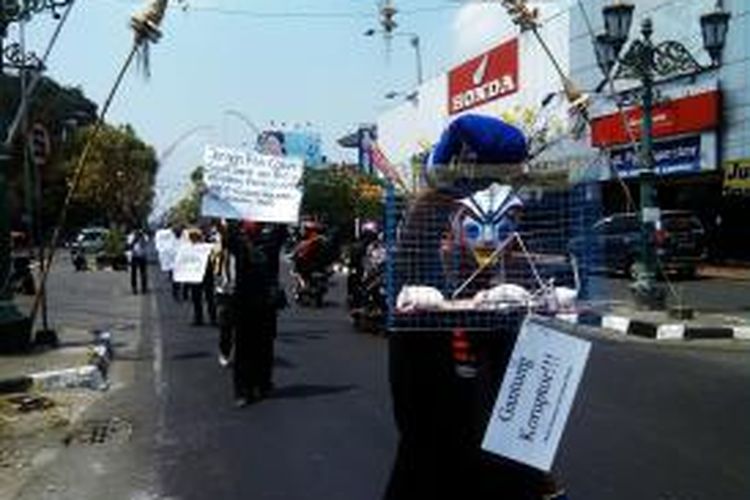 Aktivis anti korupsi Yogyakarta melakukan aksi jalan mundur sambil membawa tikus putih yang dilambangkan sebagai koruptor