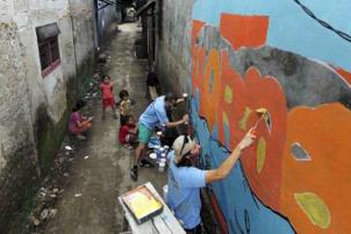 Seniman mural asal Inggris, Seb Toussaint (atas), dan Spag asal Perancis beraksi di tembok rumah penduduk di RW 004 Kelurahan Cipinang Melayu, Kecamatan Makasar, Jakarta Timur, Jumat (2/8/2013). Toussaint dan Spag berkolaborasi melukis tembok rumah penduduk di perkampungan padat di kota-kota besar di dunia. Selama tiga minggu keduanya berada di Jakarta.