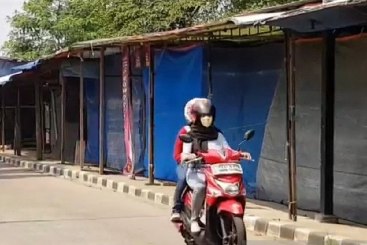 Pengendara motor melintas di depan lapak pedagang kaki lima yang berdiri di atas saluran air bantaran Kanal Banjir Timur, Duren Sawit, Jakarta Timur, Senin (20/7/2020). 