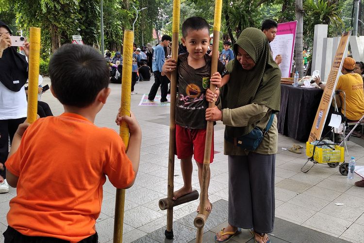 Faizan bersama ibunya, Lupi saat pertama kali mencoba egrang di event Car Free Day (CFD) Taman Bungkul, Surabaya, Minggu (23/2/2025)