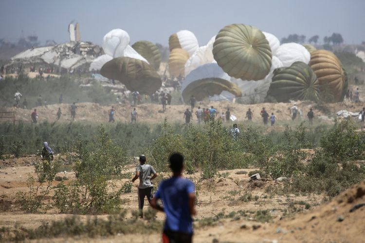 Warga Palestina berlari menuju paket bantuan kemanusiaan yang diterjunkan dari pesawat dengan parasut agar mendarat di wilayah Nuseirat, tengah Jalur Gaza, yang sedang diblokade Israel pada 6 Agustus 2025.