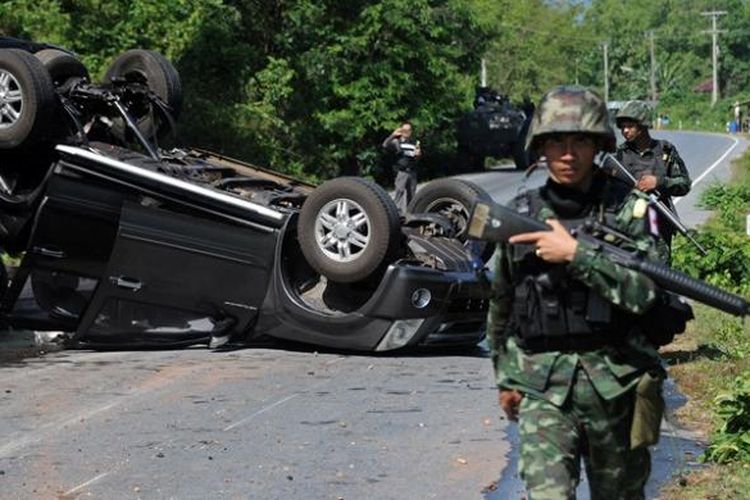 Para prajurit Thailand berjalan melintasi bangkai mobil pick-up yang hancur akibat serangan bom pinggir jalan di provinsi Narathiwat, Thailand Selatan. Sejumlah provinsi di Thailand Selatan selama bertahun-tahun menjadi pusat pemberontakan melawan pemerintah Bangkok.