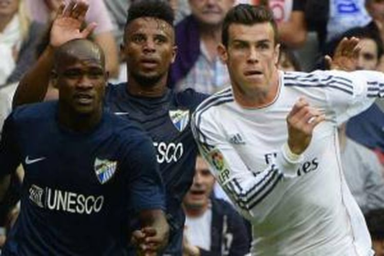 Pemain Real Madrid asal Wales, Gareth Bale (kanan), beradu dengan pemain Malaga asal Pantai Gading, Bobley Anderson, dalam pertandingan La Liga di Santiago Bernabeu, Sabtu (19/10/2013). Madrid menang 2-0.
